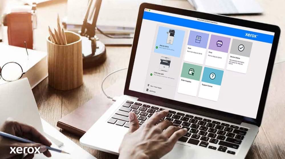 Expérience d'impression et de numérisation Xerox® : contrôle intuitif Les mains d'une personne sont posées sur un clavier d'ordinateur portable et l'écran affiche l'interface Xerox Print and Scan Experience avec des options telles que Numériser, Imprimer, État de l'appareil, Commander des fournitures et Centre d'assistance, indiquant un contrôle convivial.